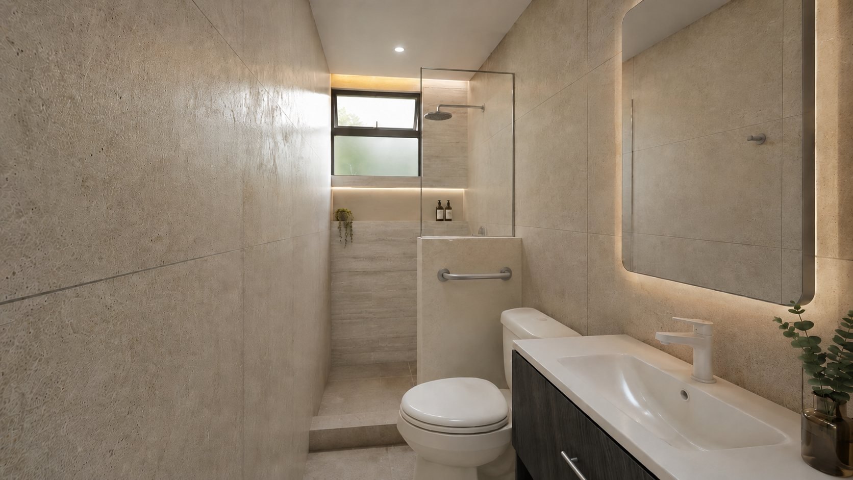 Baño en tonos arena y piedra con murete de regadera, barra de seguridad integrada y espejo retroiluminado.
